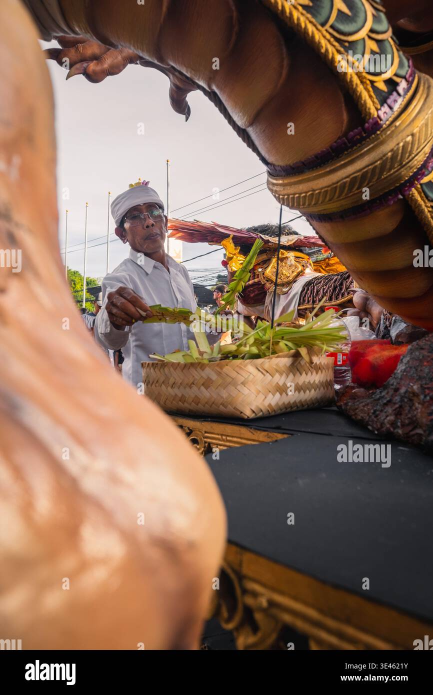 Un uomo in abiti tradizionali balinesi prega per il suo ogoh-ogoh, 18 marzo 2026, Bali, Indonesia Foto Stock