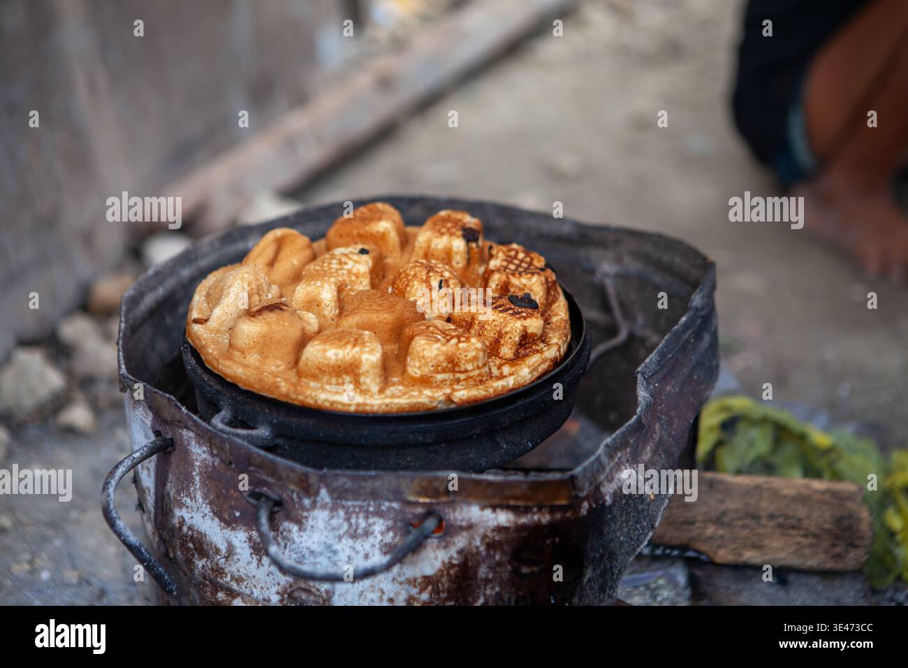 Le tradizionali torte di pastella cucinano in padella metallica sopra una stufa a carbone nell'insediamento costiero di Badjao a Mambaling, Cebu, Filippine, 2013. Foto Stock