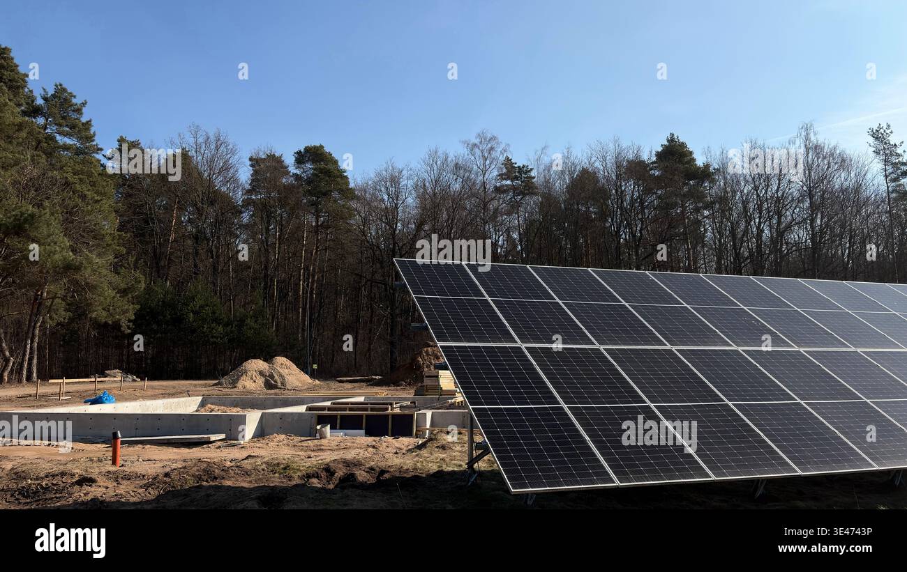 Installazione di pannelli solari in cantiere vicino alla foresta, sistema di energia rinnovabile per eco-House, moduli fotovoltaici, edifici sostenibili Foto Stock