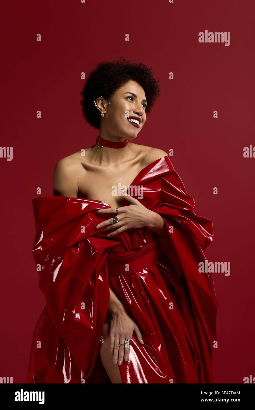 Una donna giovane e bella sfoggia un'eleganza elegante mentre sorride brillantemente in un look rosso. Foto Stock