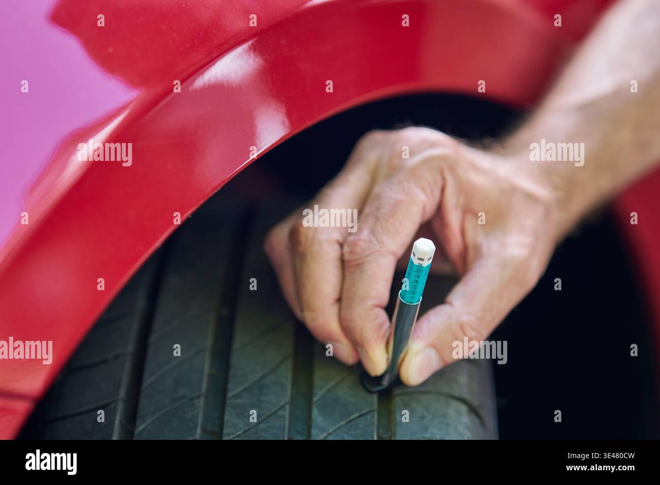 Primo piano di MAN con l'indicatore per controllare la profondità del battistrada degli pneumatici sulla vettura Foto Stock