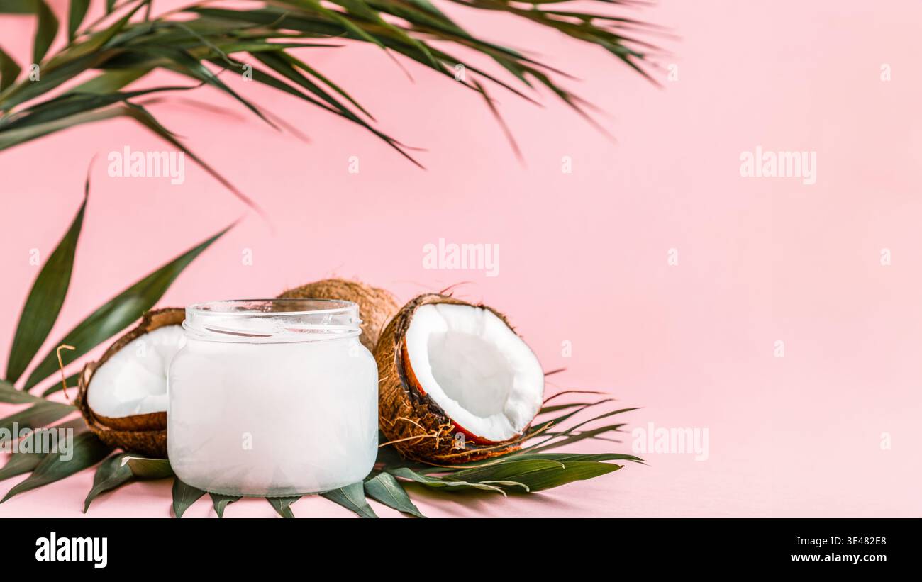 Olio di noce di cocco e noci di cocco su un brillante sfondo color pastello, il fuoco selettivo. Foto Stock
