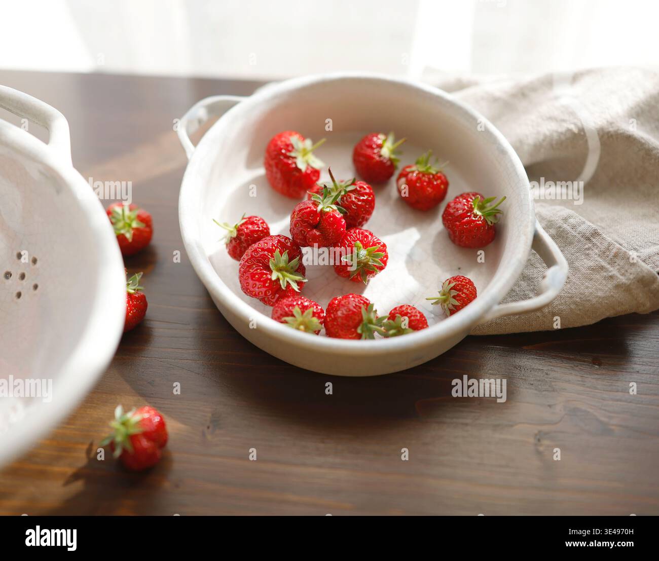Fragole rosse fresche in una ciotola vintage in ceramica bianca su un tavolo di legno scuro. La fotografia estetica del cibo mostra i frutti di bosco estivi biologici per una vita lenta Foto Stock