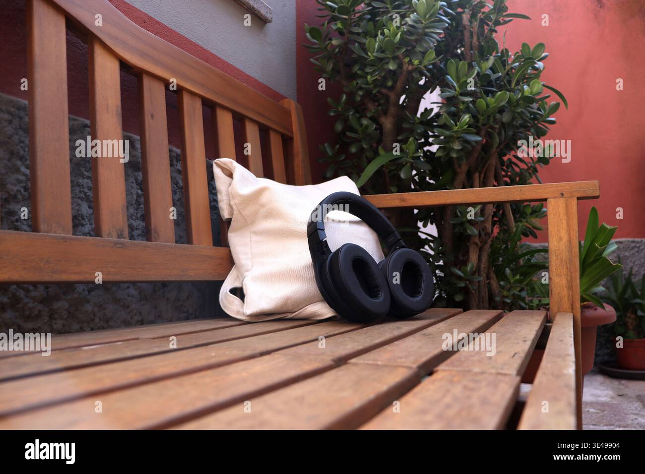 Cuffie posizionate su una panca di legno con borsa in terrazza all'aperto. Scena del tempo libero per ascoltare musica, educare, rilassarsi, vivere una pausa Foto Stock
