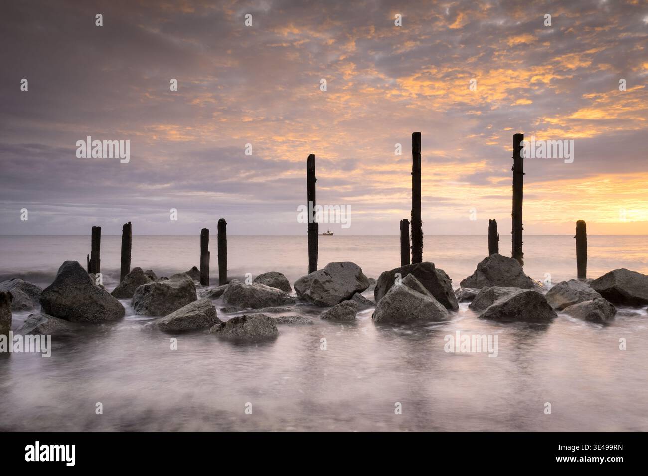 Fotografia dell'alba del primo mattino delle difese marittime in legno e roccia a Happisburgh sulla costa del Norfolk nel Regno Unito, utilizzando colori smorzati. Foto Stock