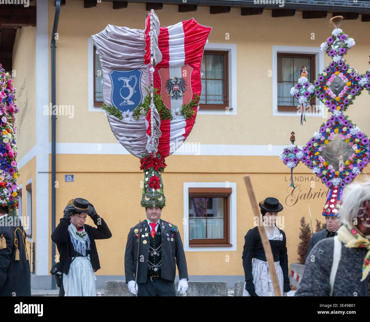AUSTRIA, SALZBURGER LAND, BAD GASTEIN - 1 GENNAIO 2026: Partecipanti tradizionali al festival con striscioni ornamentali nella piazza del paese Foto Stock