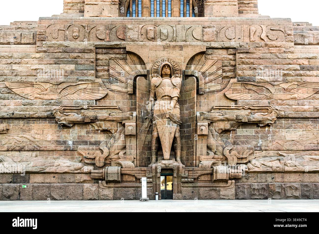 Portale d'ingresso del Monumento alla Battaglia delle Nazioni: Primo piano della figura centrale di un cavaliere con spada e scudo, fiancheggiato da rilievi alati e sculture di leoni; iscrizione sull'architrave. Il monumento commemora la battaglia delle Nazioni del 1813. Lipsia, Sassonia, Germania Foto Stock