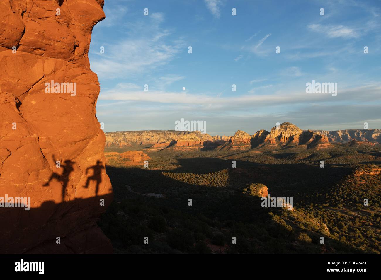 Le persone ombre con una gamba sollevata su un muro di arenaria rossa vicino a Sedona, Arizona, nel tardo pomeriggio Foto Stock