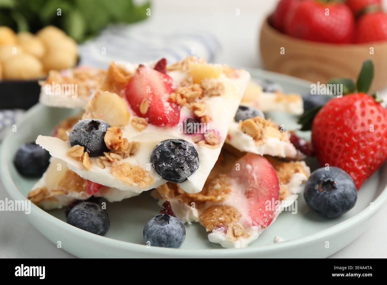 Pezzi di gustosa corteccia di yogurt con frutti di bosco e muesli sul tavolo leggero, primo piano Foto Stock