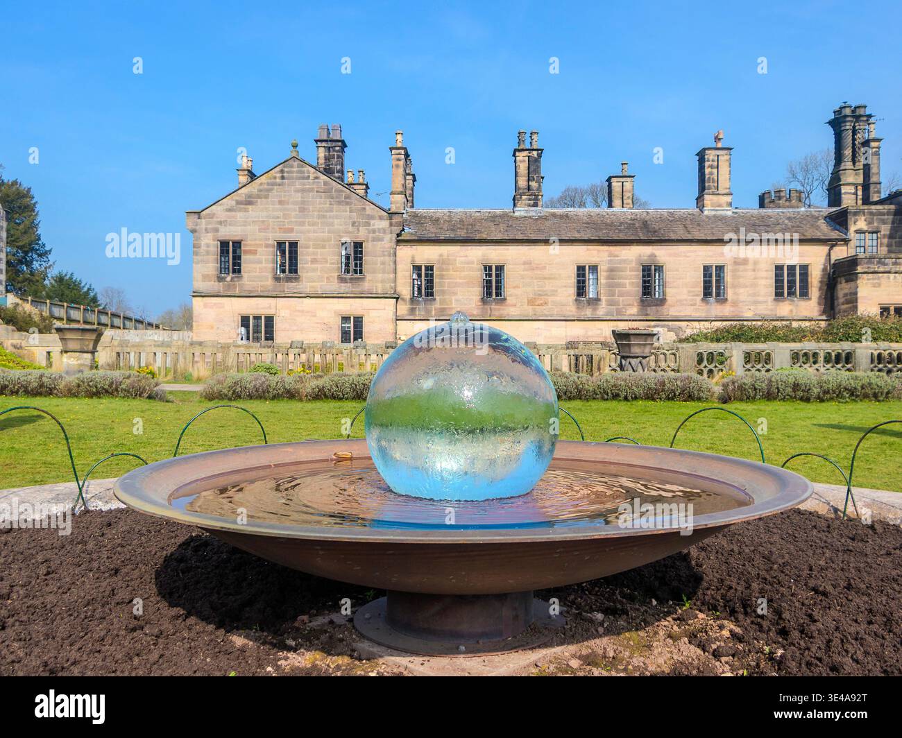 Fontana sferica in vetro nei giardini di Ilam Hall sotto un cielo azzurro nel Derbyshire in Inghilterra Foto Stock