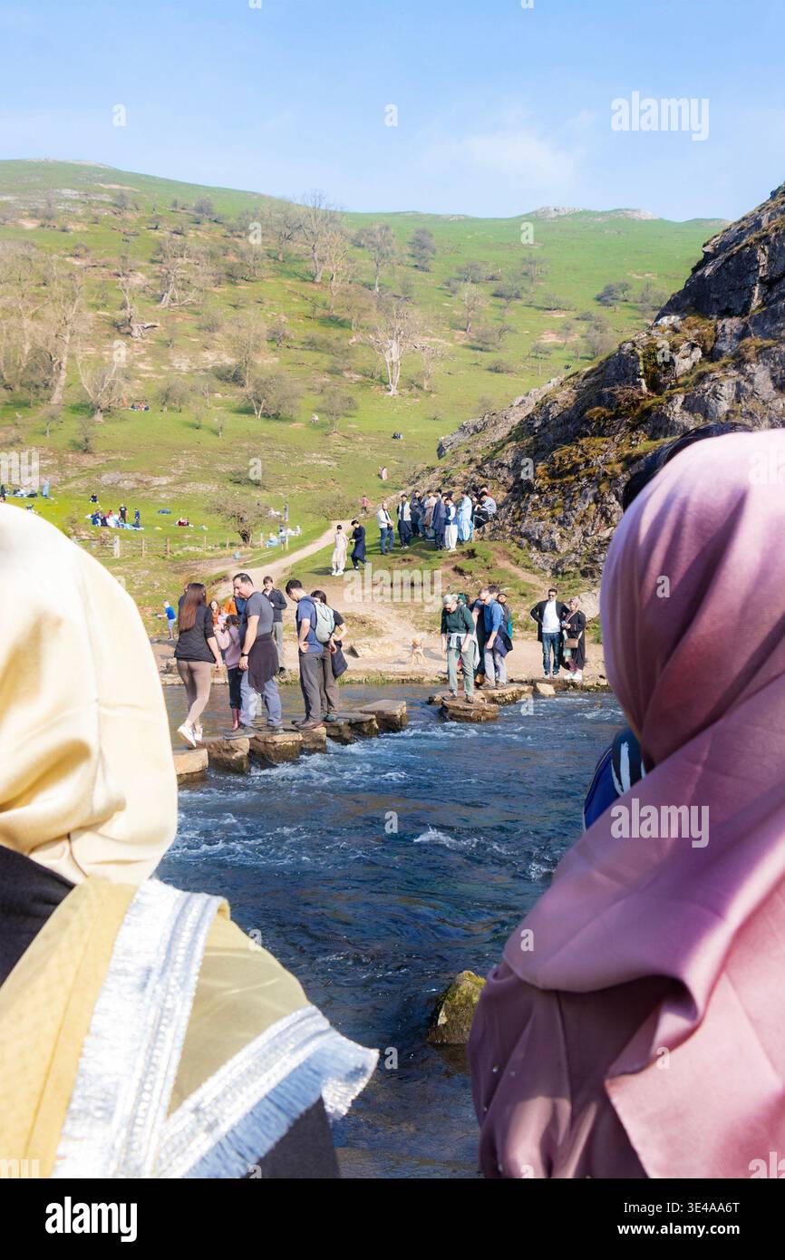 Folla di turisti musulmani che attraversano le pietre di Dovedale attraverso il fiume dove nel Peak District National Park EID muslim Foto Stock