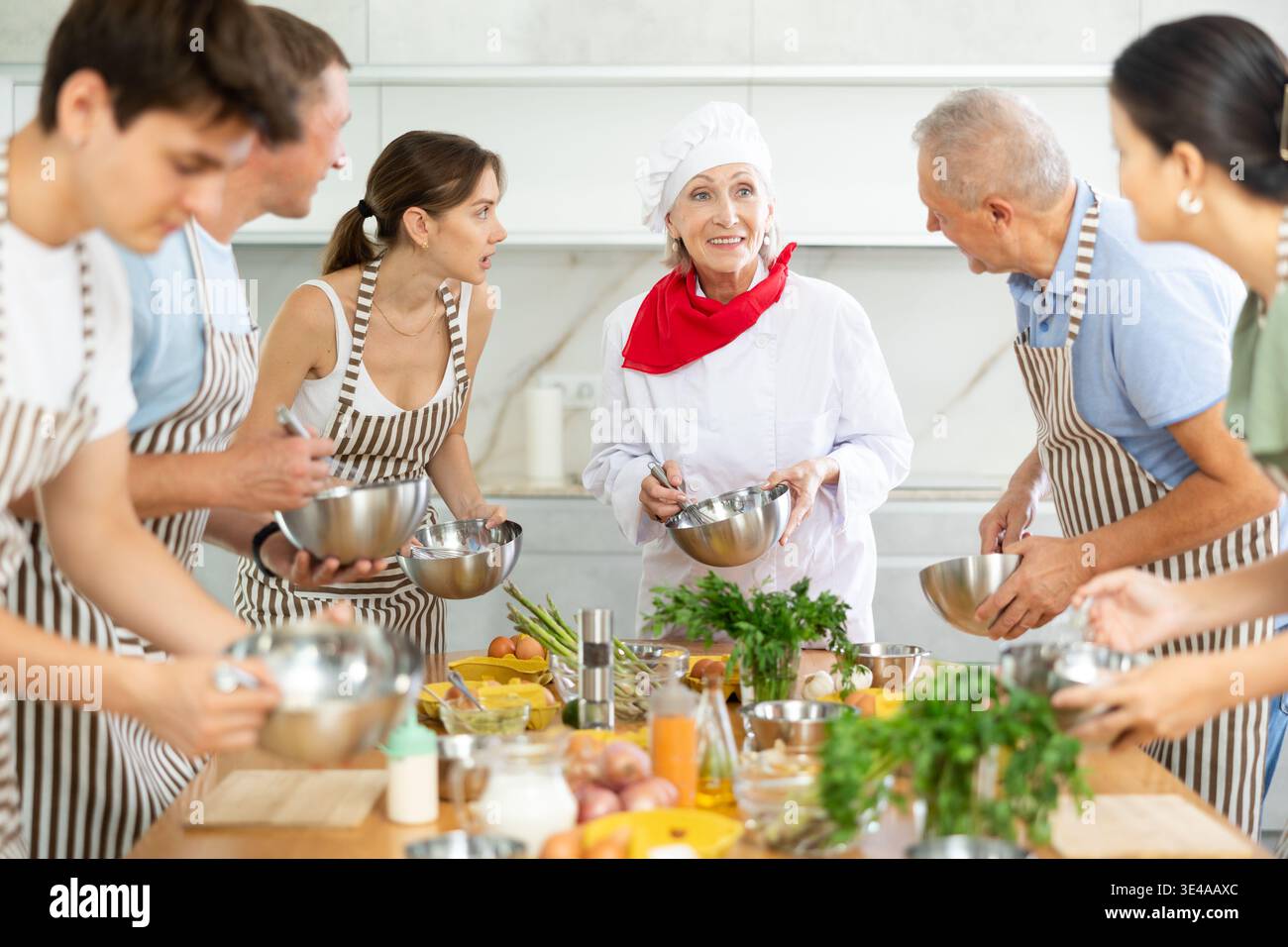 Amabile chef senior che gestisce corsi di cucina di gruppo Foto Stock