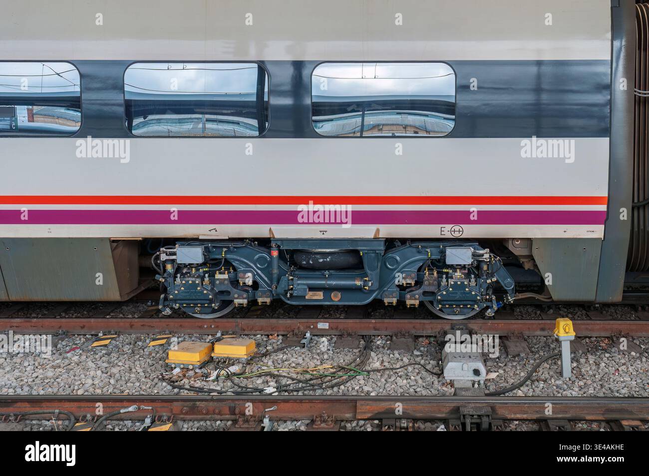 Primo piano di un lato della carrozza ferroviaria Renfe alla stazione di Valladolid-campo grande, che mostra l'assemblaggio del carrello ruota e l'infrastruttura dei binari. Foto Stock