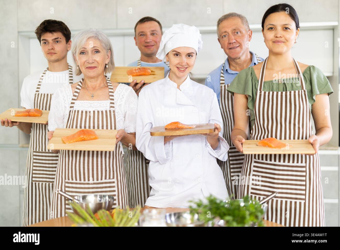 Chef sorridente che posa insieme ai partecipanti al corso di cucina Foto Stock