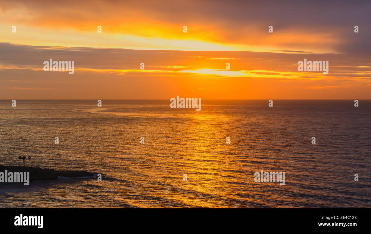 Una tranquilla fotografia di Tarragona, Spagna, che cattura un piccolo promontorio fiancheggiato da palme affacciato sul Mar Mediterraneo all'alba. La scena è f Foto Stock