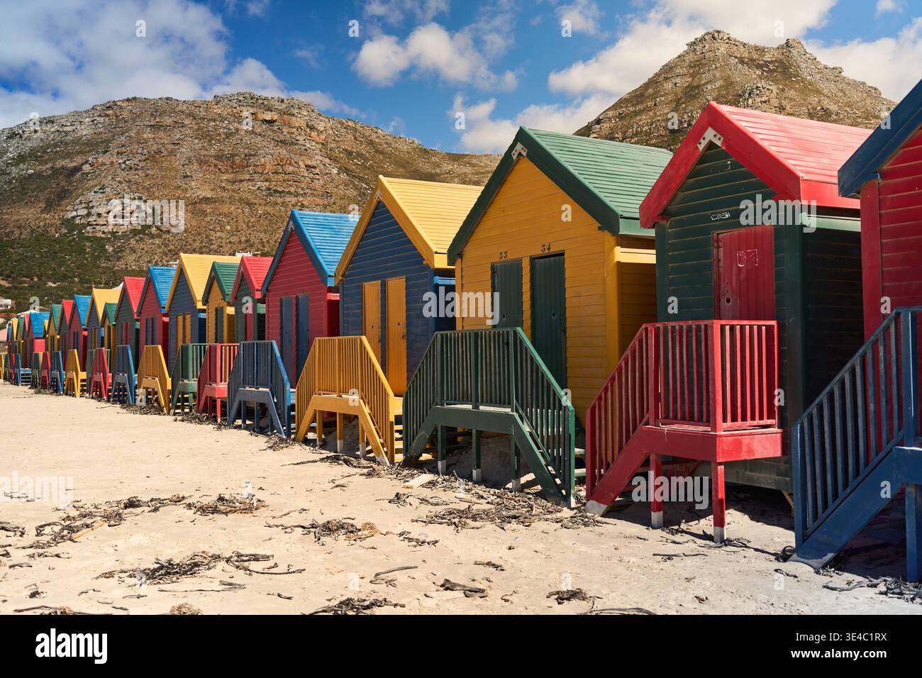 Cabine Vivid Seaside. Colorate capanne lungo la Sandy Coast. Ripari luminosi in legno sulla spiaggia con vista sulle montagne Foto Stock