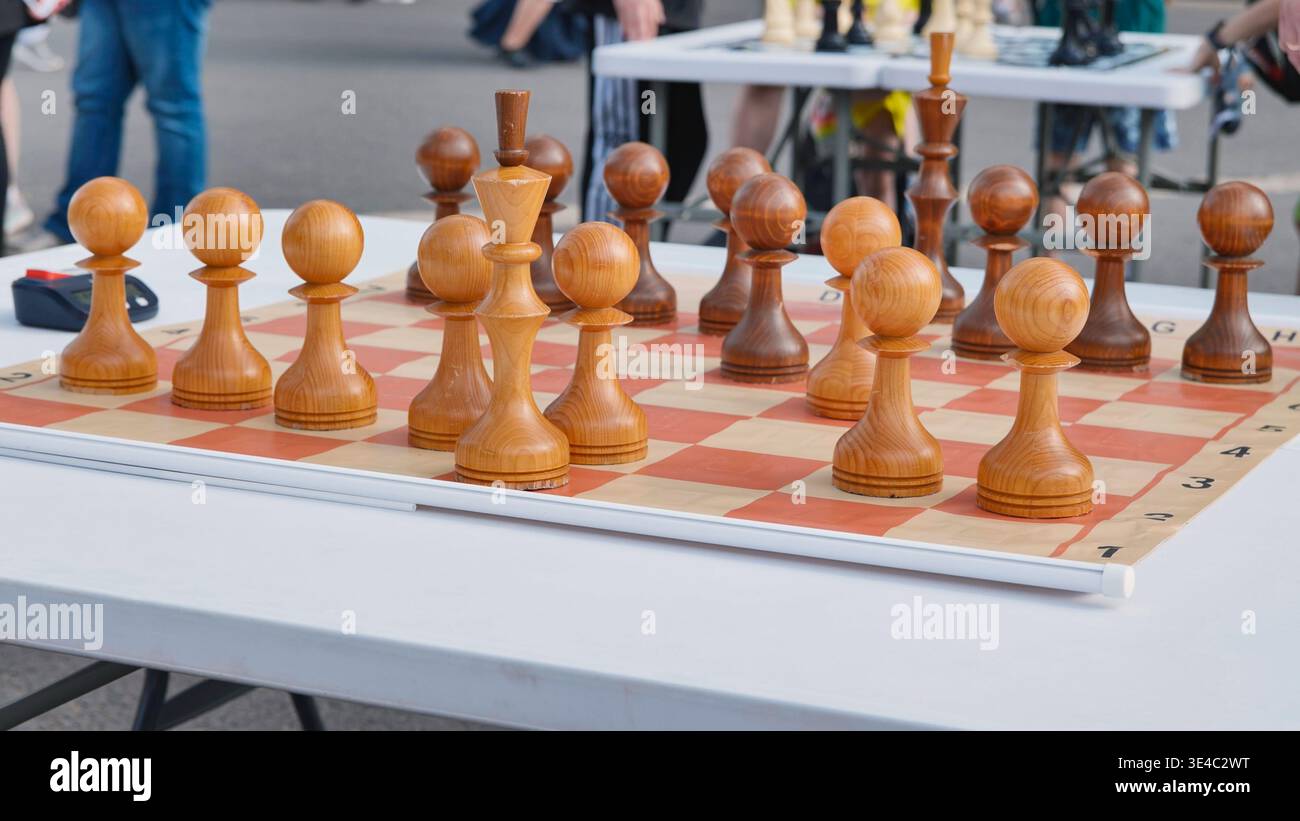 Scacchi di legno su un tabellone, pronti per una partita strategica all'aperto Foto Stock