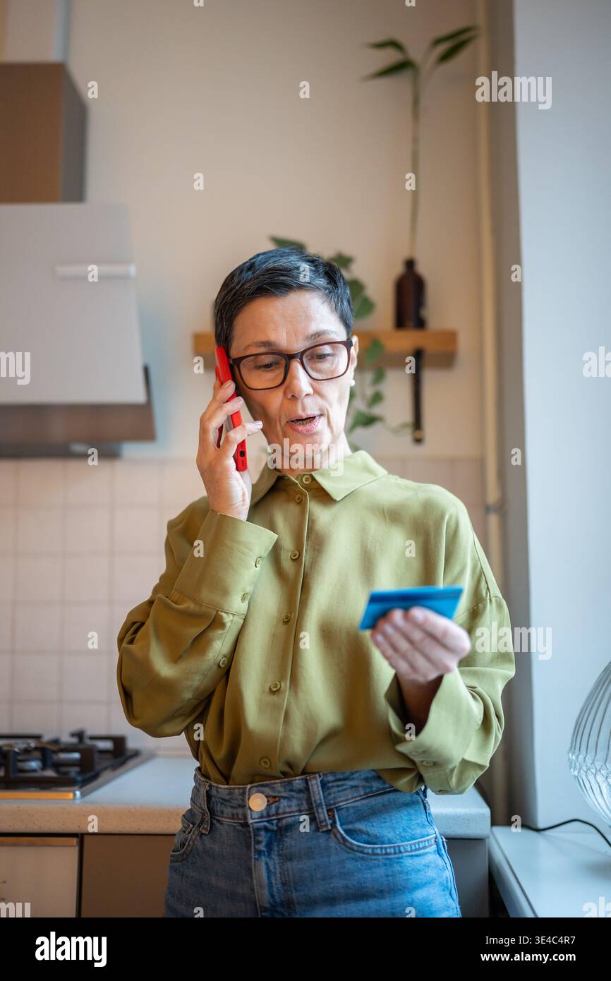 Donna anziana preoccupata che parla su smartphone con truffatori finanziari, che condivide i dati personali con i furti Foto Stock