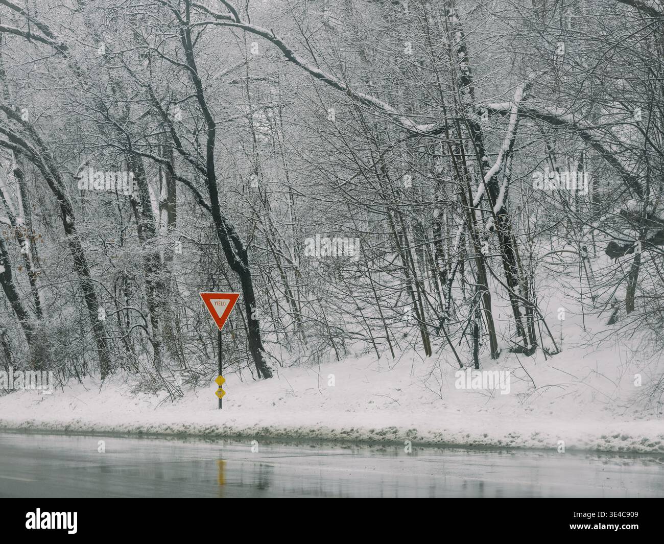 Segnale di snervamento su una strada innevata durante una tormenta invernale Foto Stock