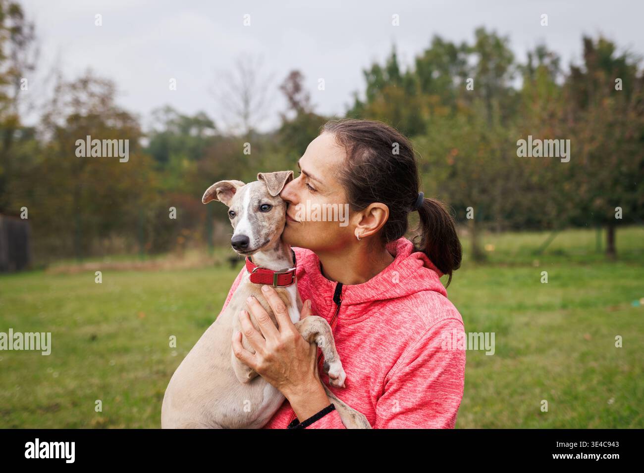Donna che abbraccia e bacia il cucciolo all'aperto. Stretto legame e amicizia tra il proprietario e il cane Foto Stock
