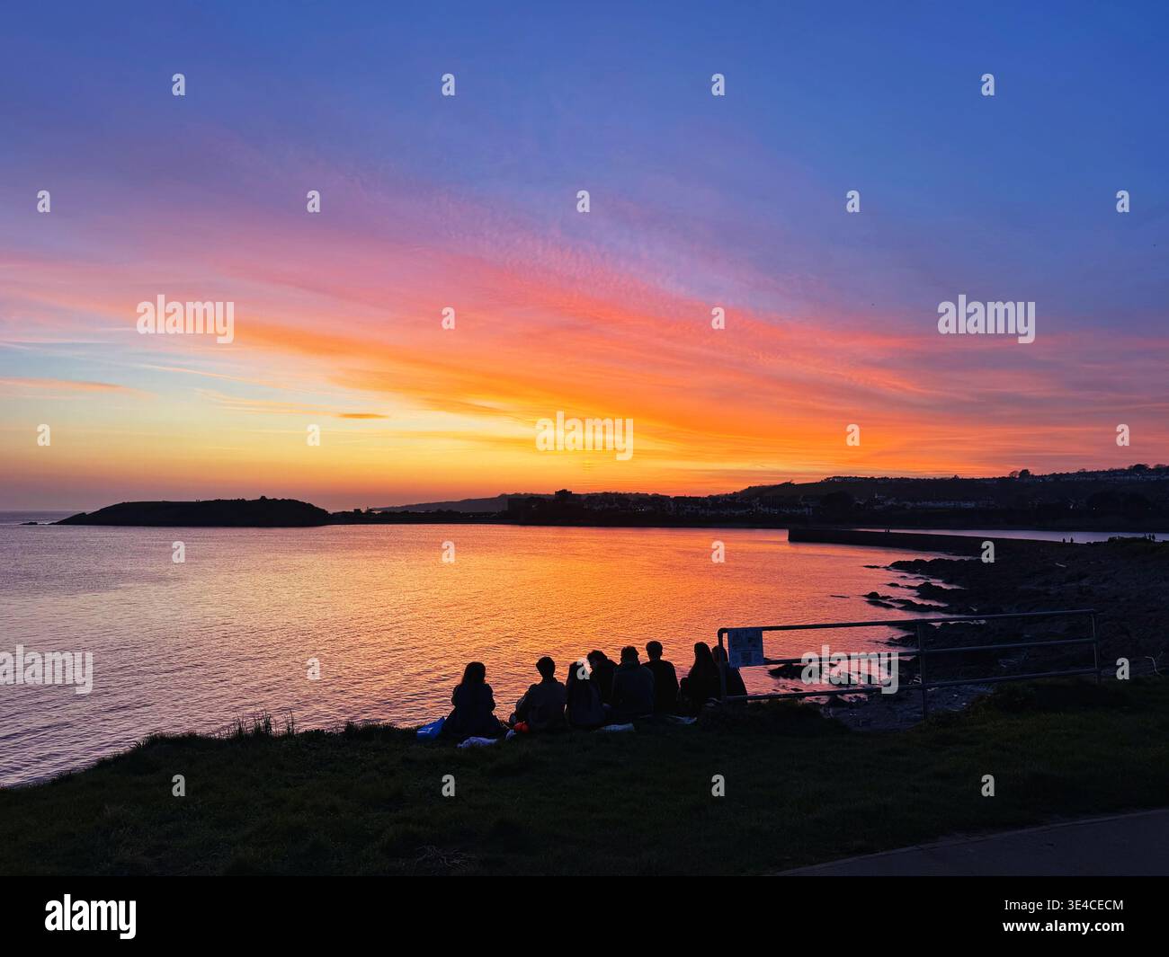 Un gruppo di giovani che si godono un bellissimo tramonto di marzo a Barry Island, Galles del Sud, Regno Unito. Foto Stock