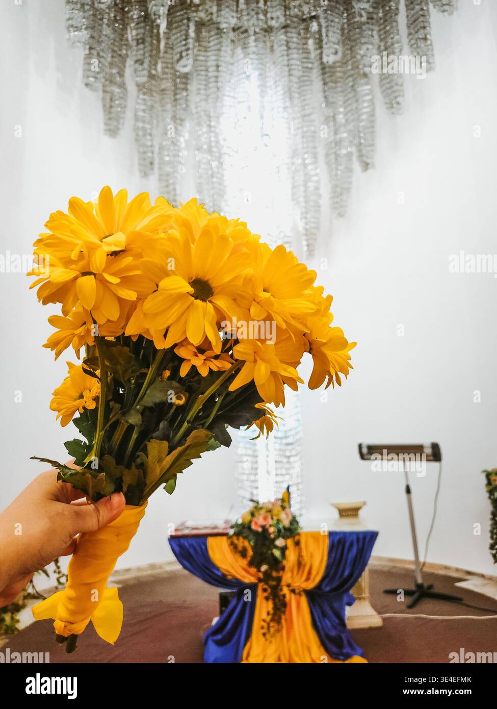 bouquet nuziale di margherite gialle nella sala per matrimoni. un piccolo bouquet di fiori selvatici autunnali nelle mani della sposa Foto Stock