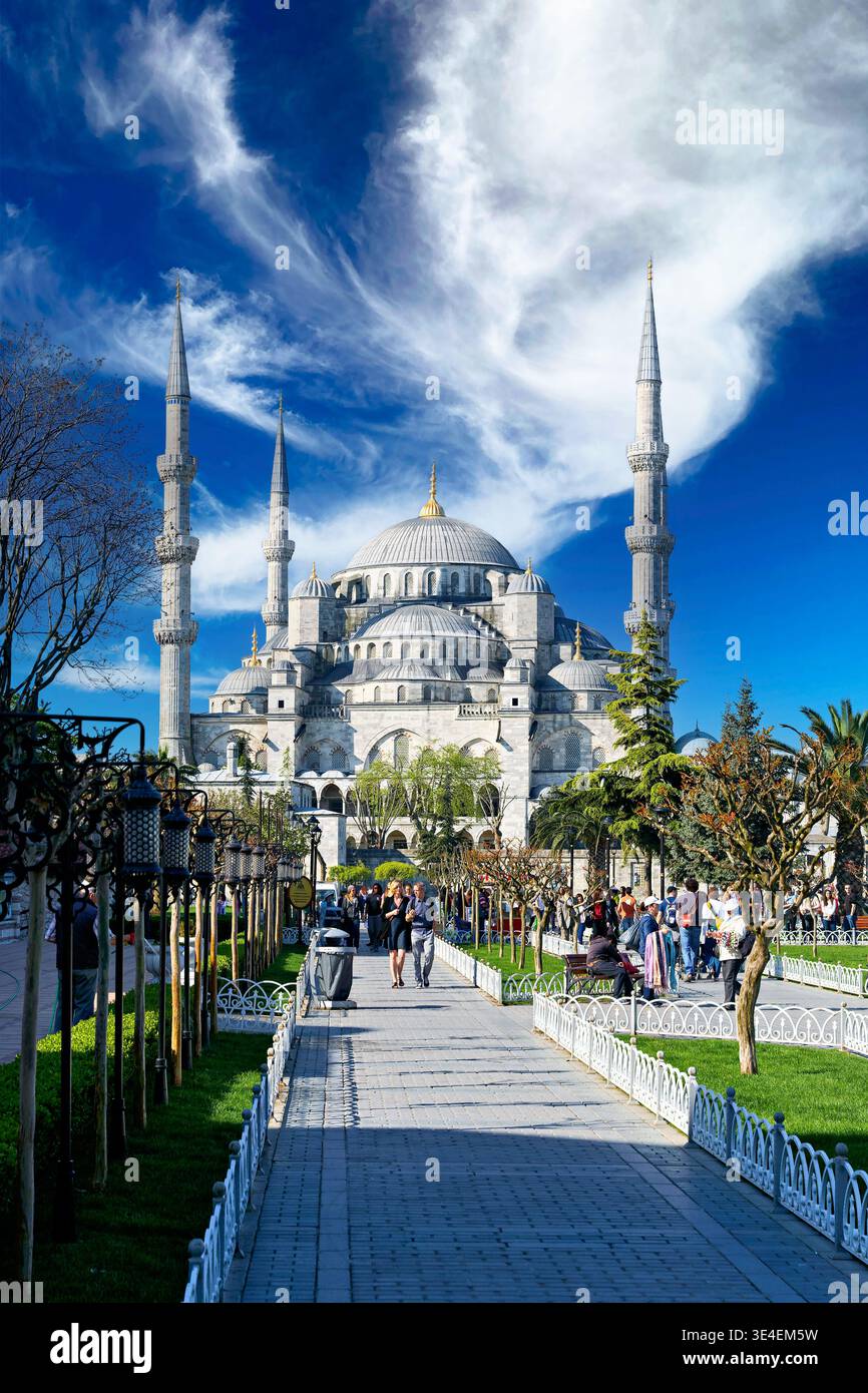 La gente cammina lungo il sentiero di fronte alla Moschea Blu di Istanbul. Il cielo limpido e gli alti minareti creano una vista suggestiva. Foto Stock