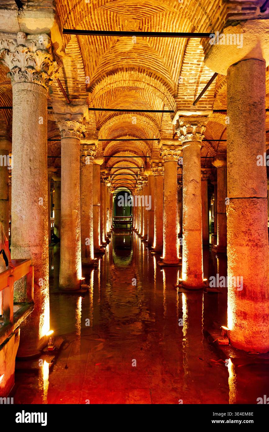 I visitatori camminano attraverso la Cisterna Basilica di Istanbul, Turchia. L'atmosfera e' scura con una calda illuminazione sulle colonne e sull'acqua. Foto Stock
