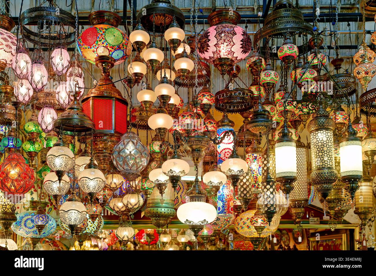Le persone camminano attraverso il Gran Bazar di Istanbul mentre le lanterne colorate si aprono sopra. L'atmosfera e' vivace e piena di oggetti in vendita. Foto Stock