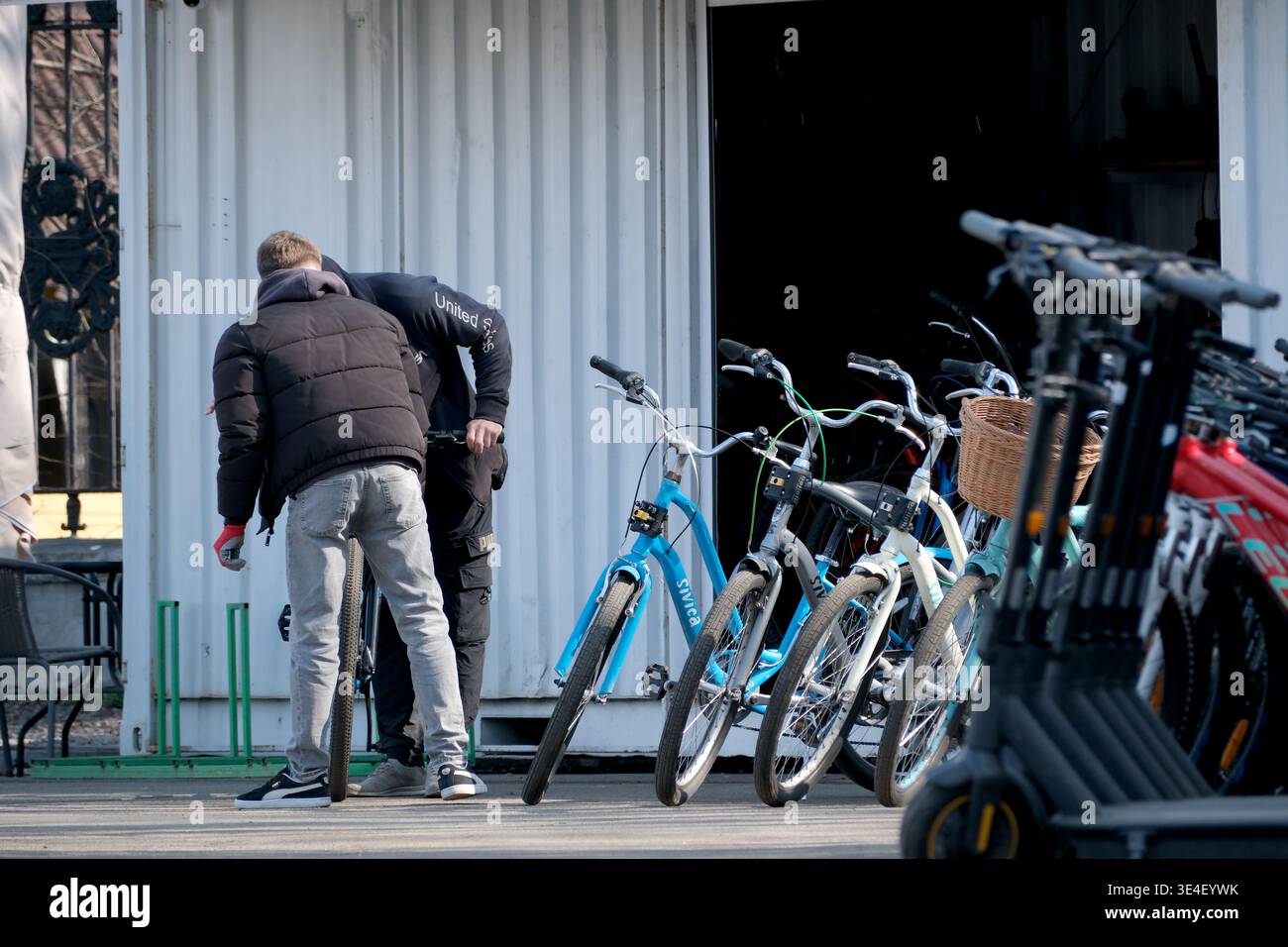 Due ciclisti chiacchierano mentre facevano controllare le loro biciclette vicino a un affollato negozio di noleggio. Ucraina, Kiev, Expocentre of Ukraine, 27 marzo 2026 Foto Stock