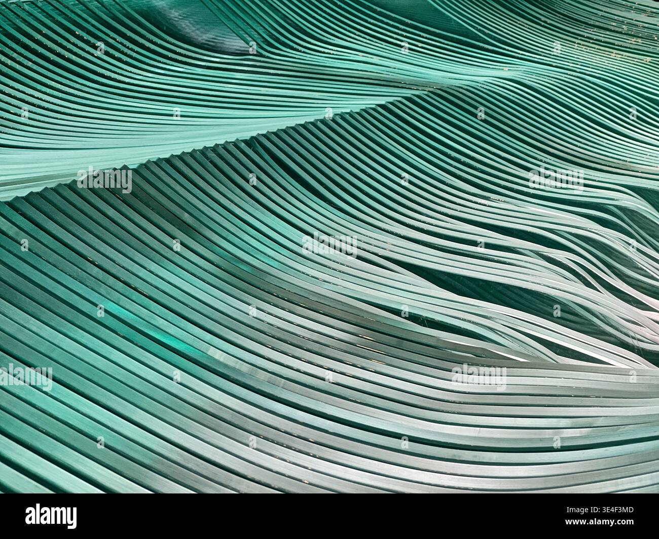 Fogli di vetro impilati insieme in strati di forme ripetute formano una forma simile alle onde oceaniche. Foto Stock