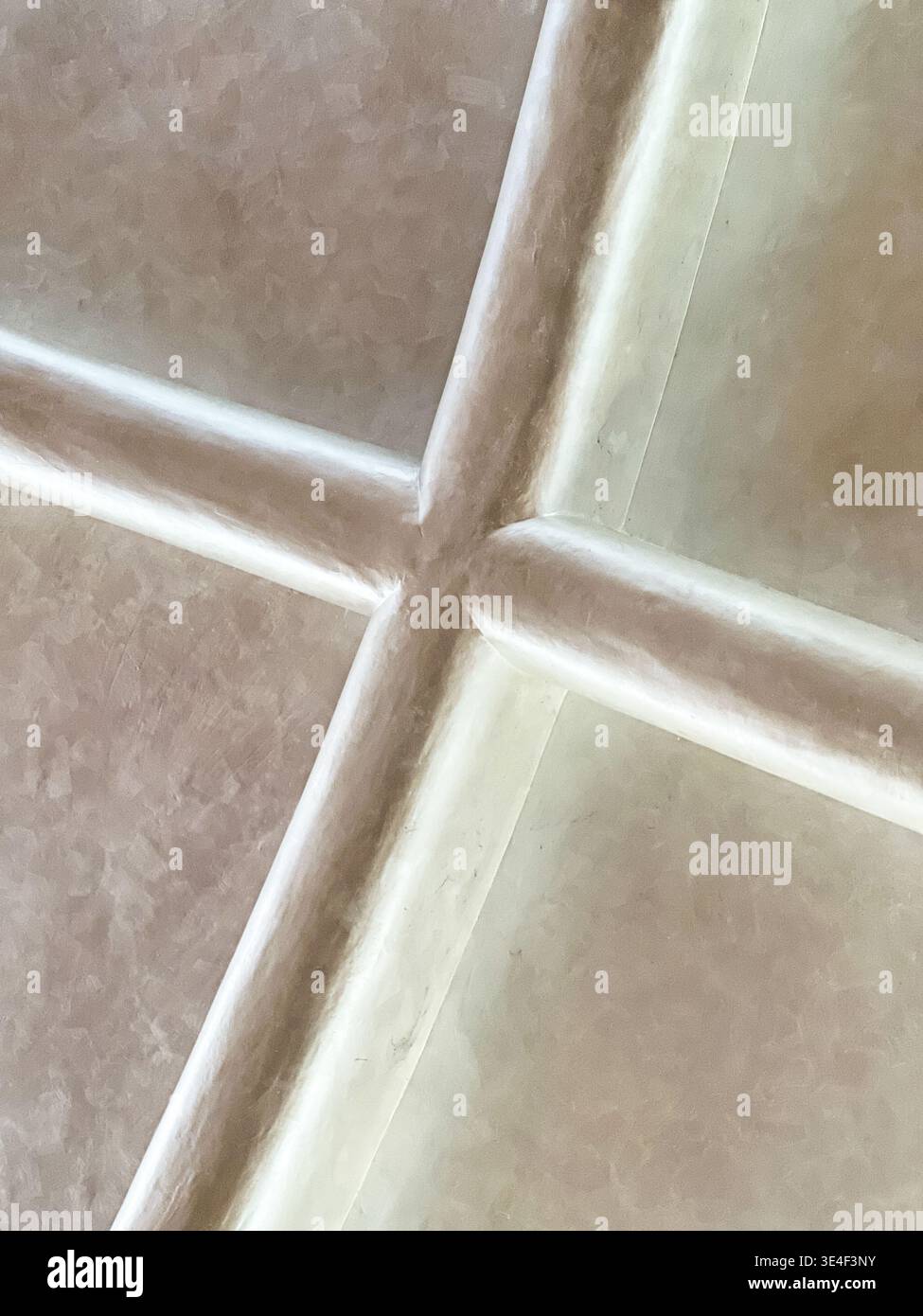 Due linee su un soffitto incrociato per formare un modello astratto con la luce e le ombre. Foto Stock