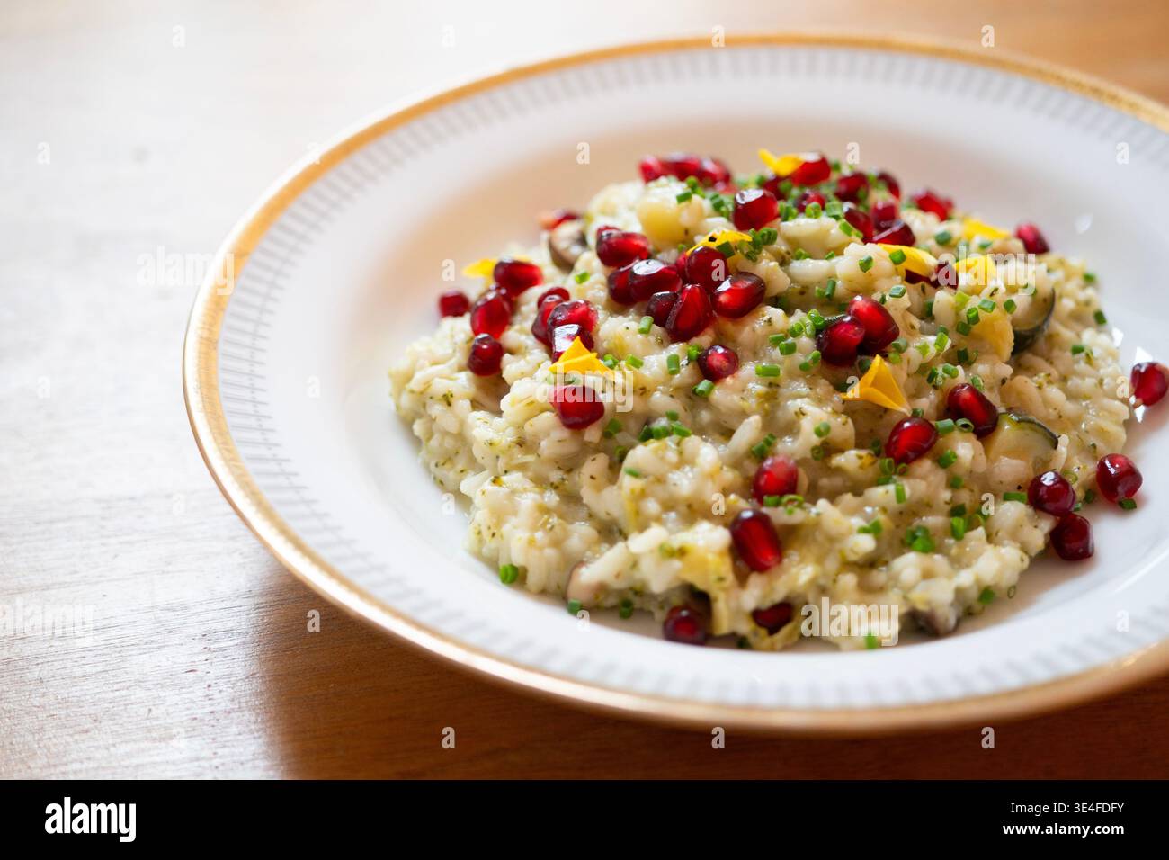 Risotto cremoso con semi di melograno ed erbe fresche servito in una ciotola bianca Foto Stock
