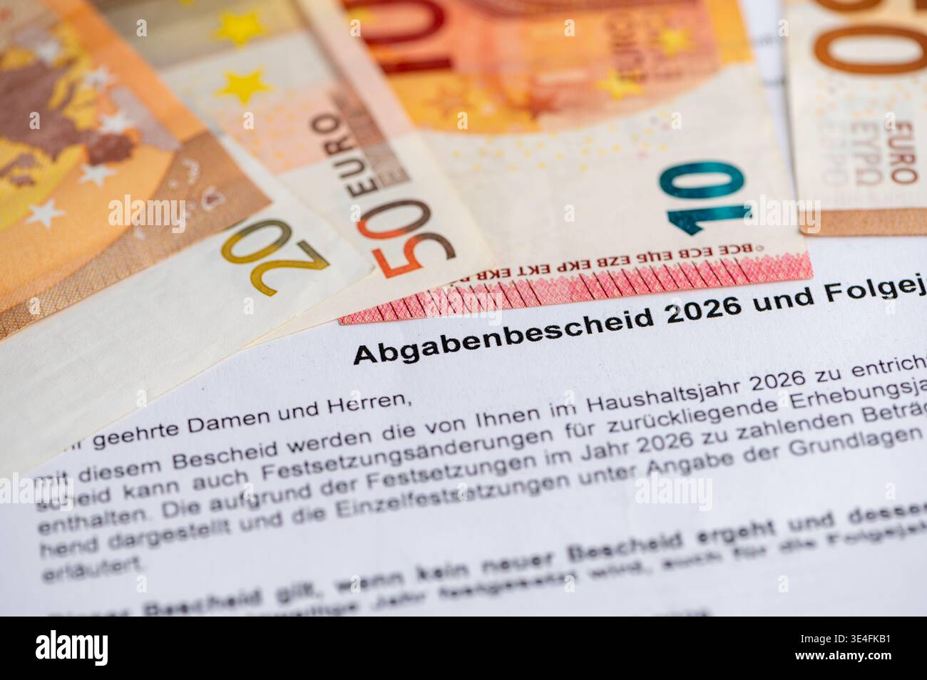 Primo piano della valutazione tedesca dell'imposta immobiliare "Abgabenbescheid" con le banconote in euro, concetto di onere finanziario Foto Stock