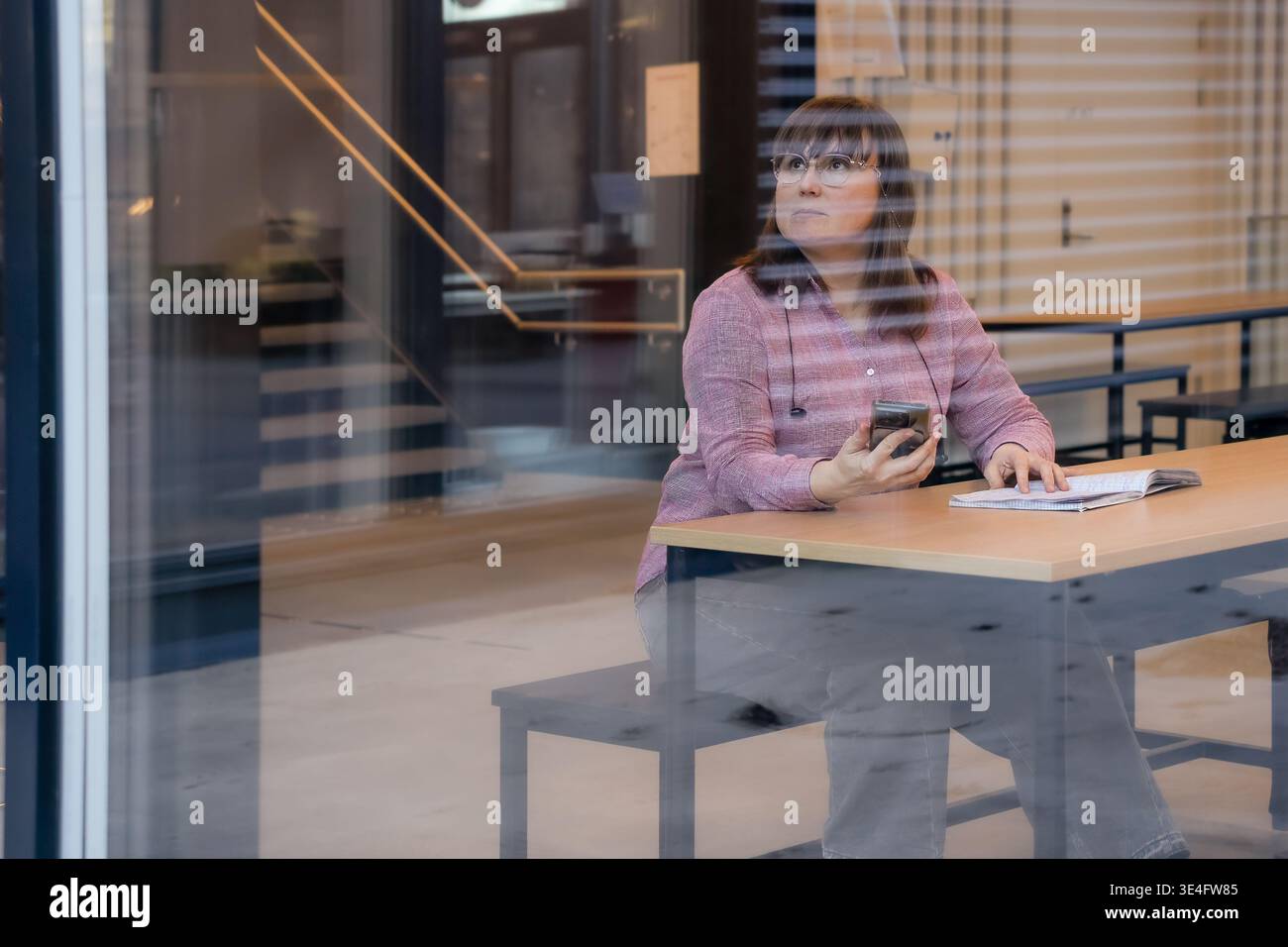 Proiezione del ruolo futuro studente di mezza età seduto al tavolo della scuola e riflettendo sui passi successivi mentre studia materiali che mostrano la pianificazione della carriera futura Foto Stock