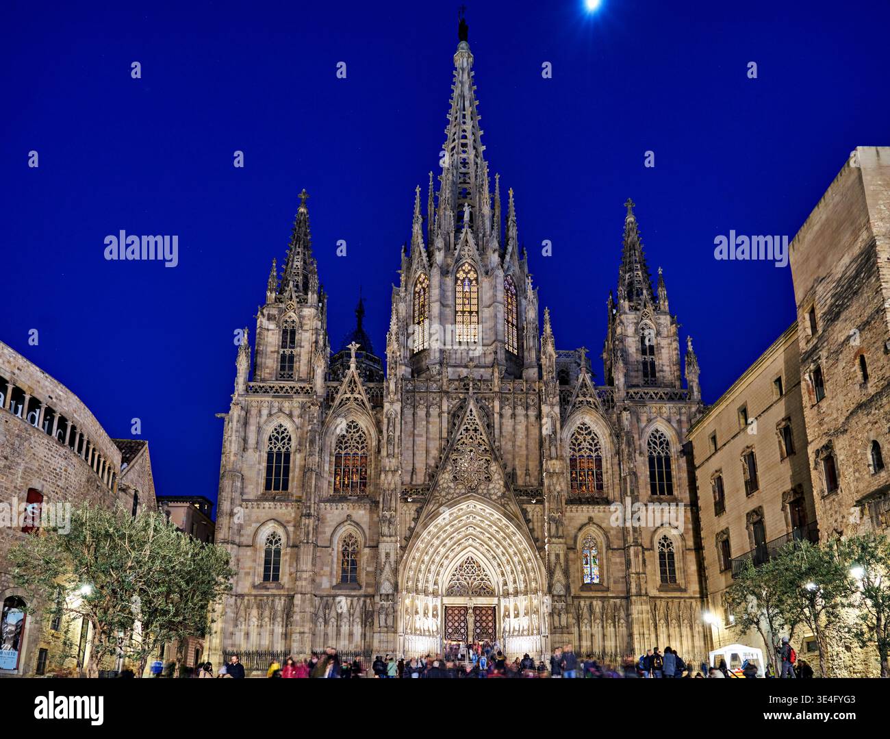 I visitatori si riuniscono presso la Cattedrale di Santa Croce e Sant'Eulalia a Barcellona durante la serata. Il cielo è blu scuro. Foto Stock