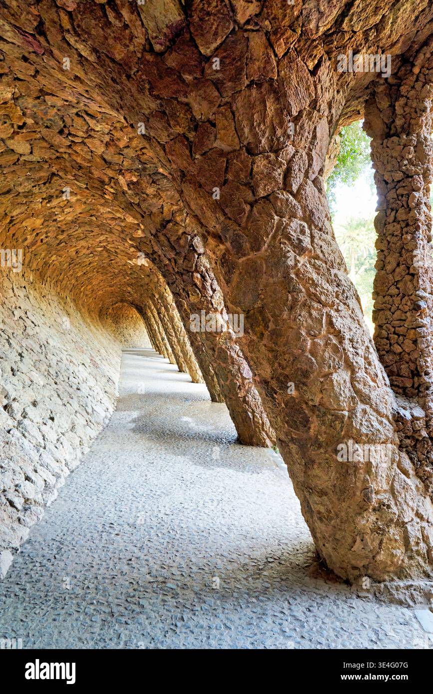 I visitatori passeggiano lungo il sentiero colonnato di Park Guell, osservando l'architettura unica di Antoni Gaudí a Barcellona, in Catalogna. Foto Stock