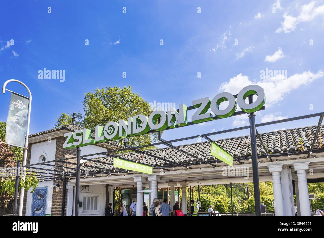 Le famiglie passano le iconiche porte dello ZSL London Zoo in una giornata di sole, con cartelli vivaci e folle perfette per le vacanze nel Regno Unito, la fauna selvatica o gli editoriali delle attrazioni. Londo Foto Stock