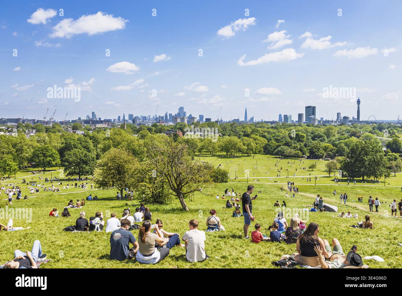 Primrose Hill, Regent's Park. Persone che fanno un picnic sull'erba con lo skyline panoramico di Londra che presenta The Shard, Walkie Talkie e BT Tower sotto un trasparente Foto Stock