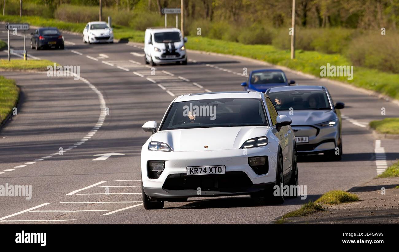 Milton Keynes,Bucks,UK - 26 marzo 2026: 2025 Porsche Macan 4 auto elettrica bianca che guida su una strada britannica Foto Stock