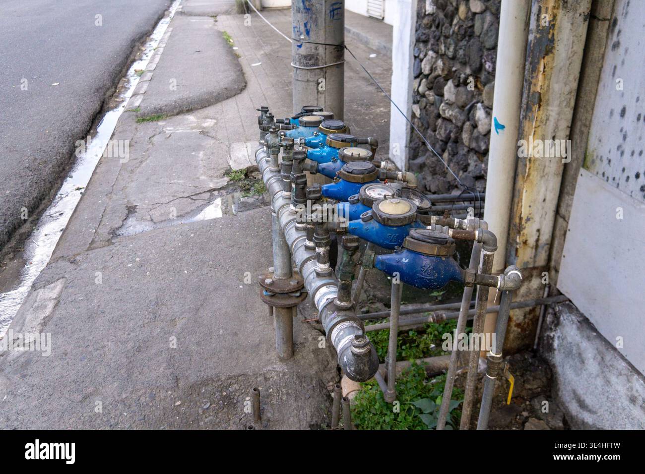 Fila di contatori d'acqua residenziali installati lungo la pavimentazione stradale a Cebu City, Filippine, che mostrano le infrastrutture urbane e l'approvvigionamento idrico pubblico. Foto Stock