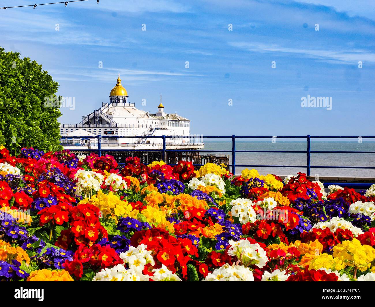 Vibrante vista estiva del molo di Eastbourne incorniciato da fiori audaci e colorati - classica architettura marittima con colori luminosi e accattivanti della costa, Foto Stock