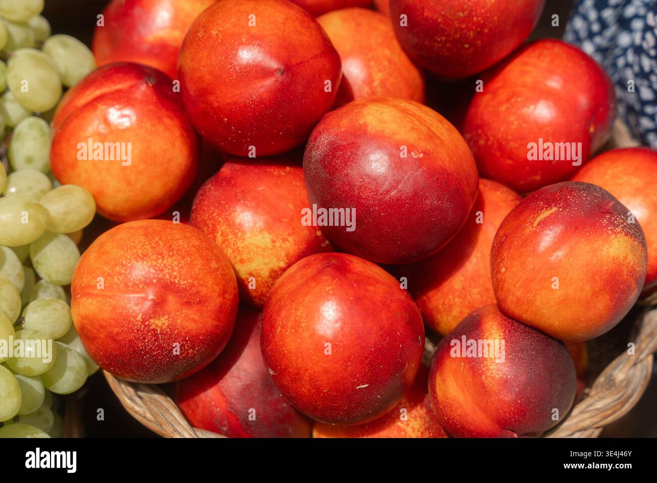 Frutta a pietra matura e uva assortite disposte in cesti presso un mercato all'aperto. Ideale per marchi di alimenti biologici, promozione di prodotti agricoli e alimentari Foto Stock
