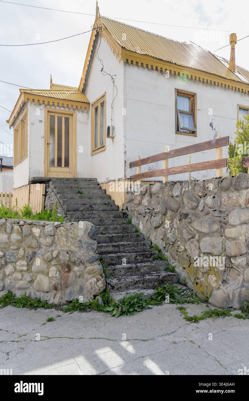 Paesaggio urbano con un edificio tradizionale con tetto in ferro ondulato e scale in pietra, girato con la luce brillante dell'estate a Ushuaia, Argentina Foto Stock