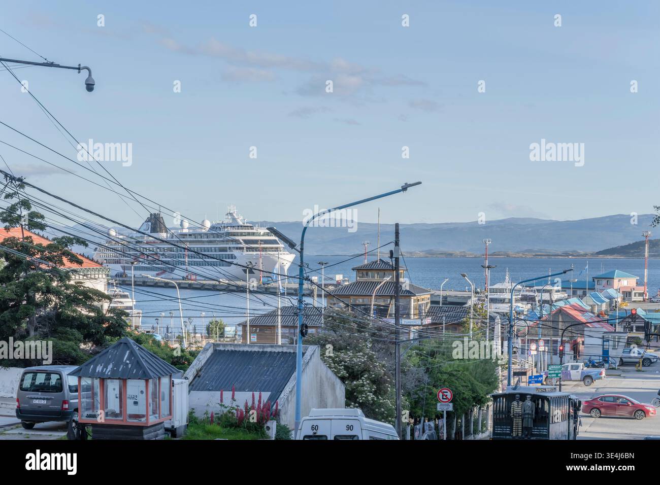 USHUAIA, 2026 gennaio 18; paesaggio urbano con nave da crociera attraccata che si infila fuori dai tetti della città, girato alla luce della sera estiva il 19 gennaio 2026 a Ushuaia, Arg Foto Stock