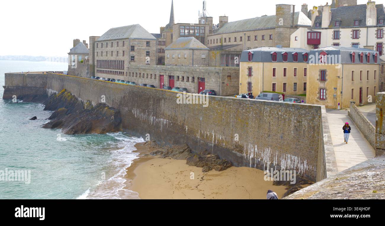 Pareti marittime fortificate e spiaggia sabbiosa con pedonale sul passaggio costiero a Saint-Malo Intra-Muros, Bretagna, Francia Foto Stock
