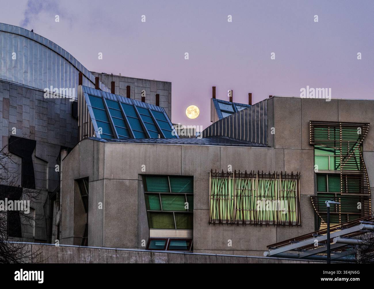 Spettacolare vista al crepuscolo dell'edificio del Parlamento scozzese a Edimburgo, caratterizzato da moderne forme di cemento e vetro con la luna piena che si innalza sopra angolari Foto Stock