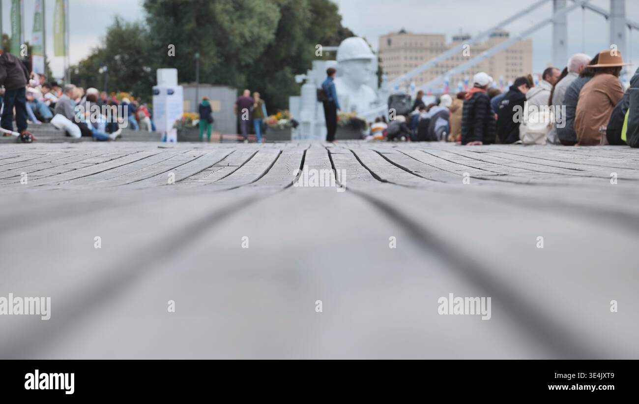 Passerella in legno che conduce a persone che si rilassano e osservano in un parco pubblico cittadino Foto Stock