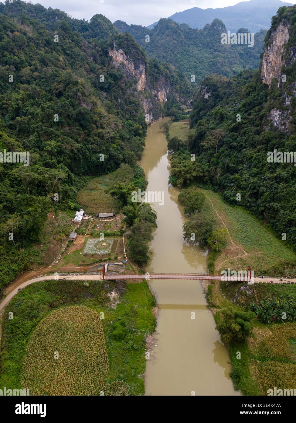 Fiume Nang, Vietnam - 16 gennaio 2024: Una vista con i droni mostra un ponte che attraversa il fiume Nang tra colline calcaree boscose e terreni agricoli. Foto Stock