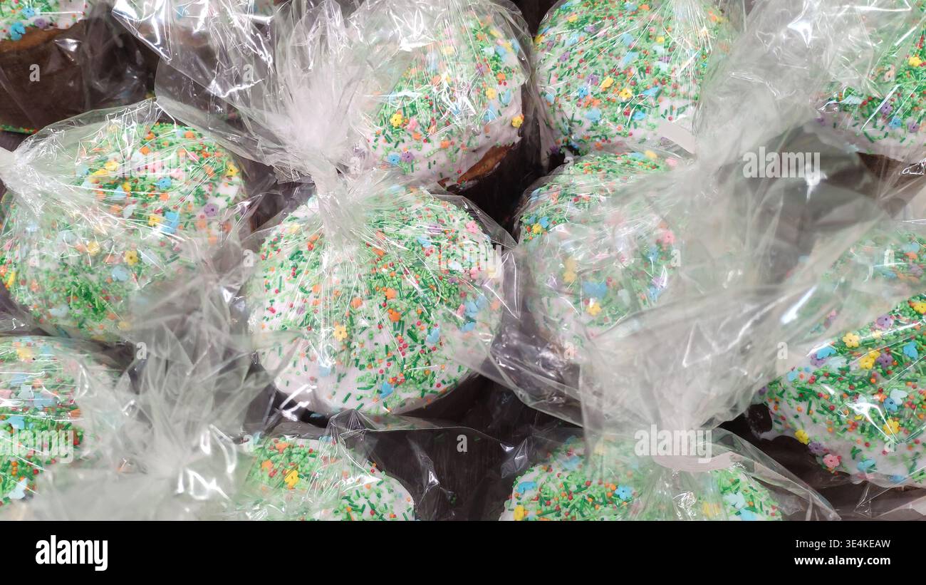 Torte di Pasqua in confezione trasparente con spruzzi luminosi. Preparatevi per Pasqua. Prodotti da forno natalizi nel negozio. Primo piano di cupcake pasquali confezionati. Foto Stock